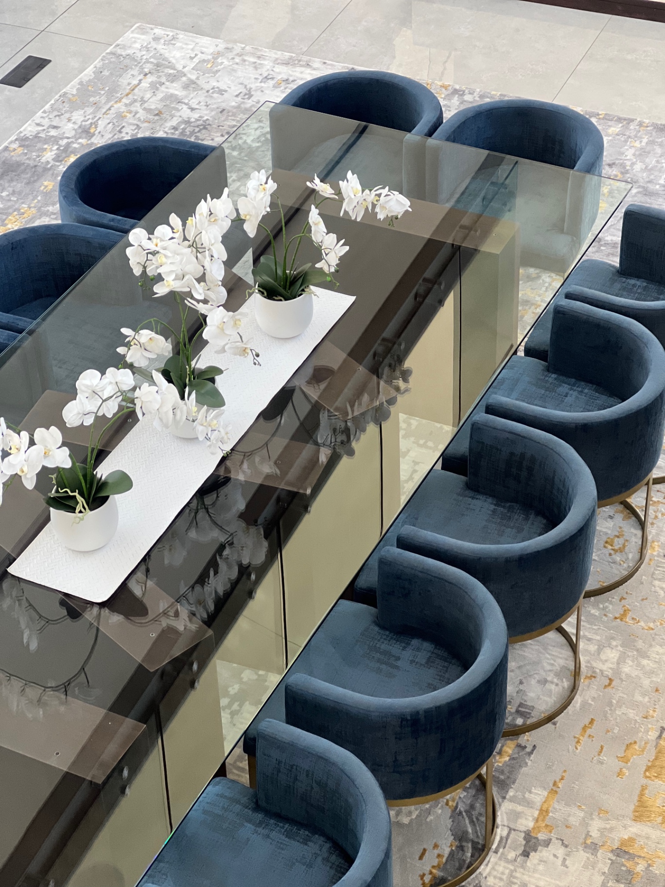 Glass dining table with bespoke blue velvet tub chairs from above