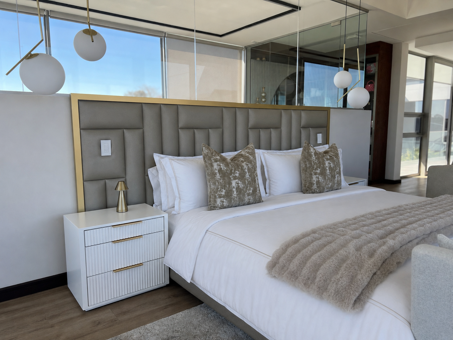 Grey channel-tufted headboard framed in brushed gold with fluted white pedestal